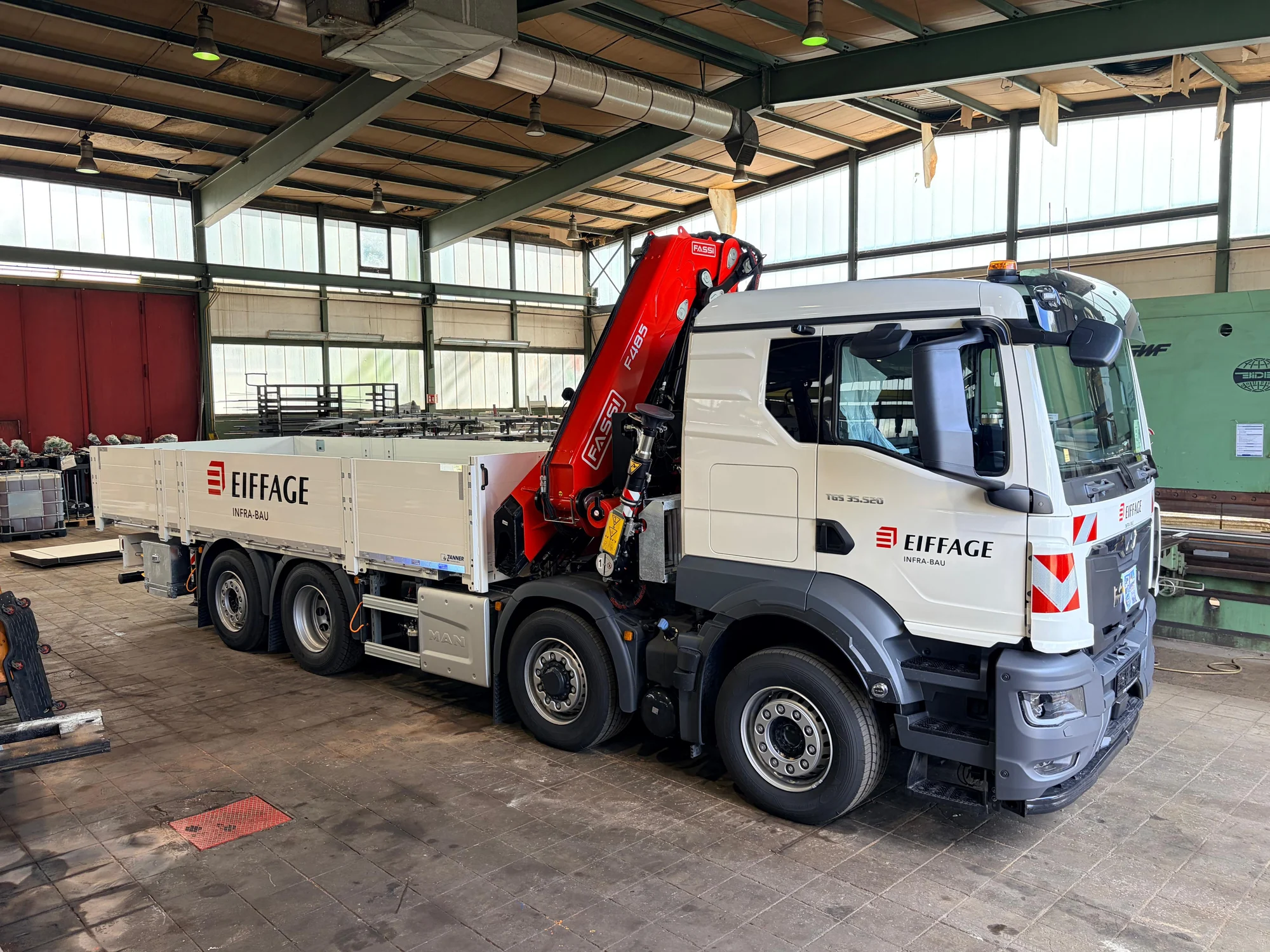 Weißer MAN-LKW mit rotem Ladekran und Eiffage-Infra-Bau-Beschriftung auf Fahrerhaus und Pritsche